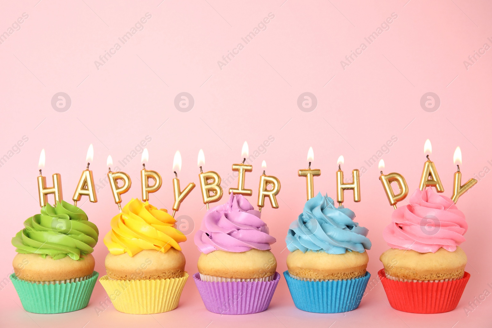 Photo of Birthday cupcakes with burning candles on pink background. Space for text