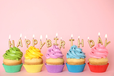 Birthday cupcakes with burning candles on pink background. Space for text