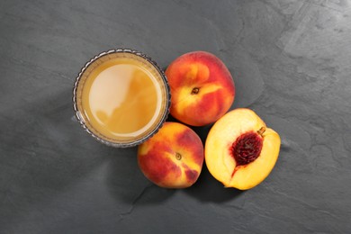 Photo of Glass of delicious peach juice and fresh fruits on black table, flat lay