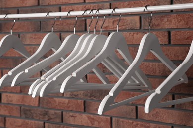 White clothes hangers on rail near red brick wall