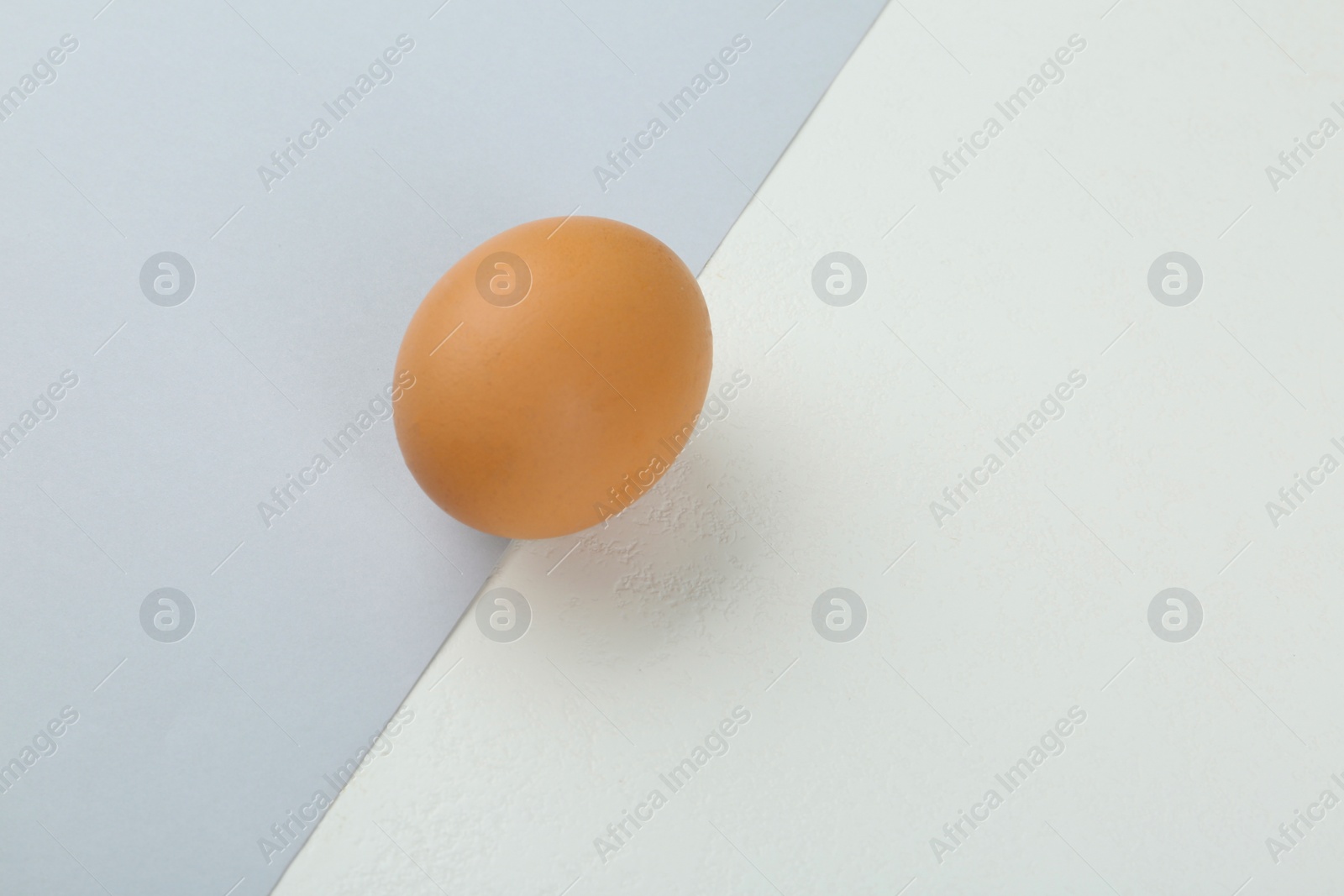 Photo of Raw chicken egg on color background, top view. Space for text