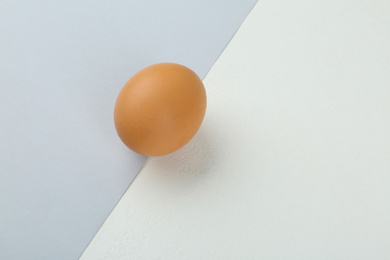 Photo of Raw chicken egg on color background, top view. Space for text