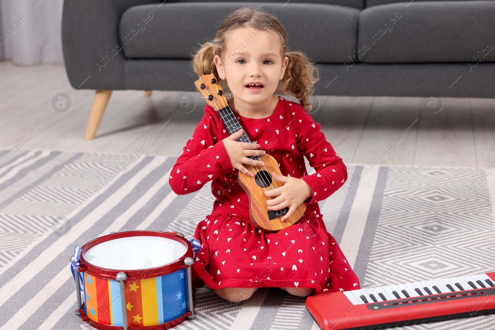 Photo of Little girl playing toy guitar at home