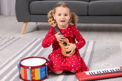 Little girl playing toy guitar at home