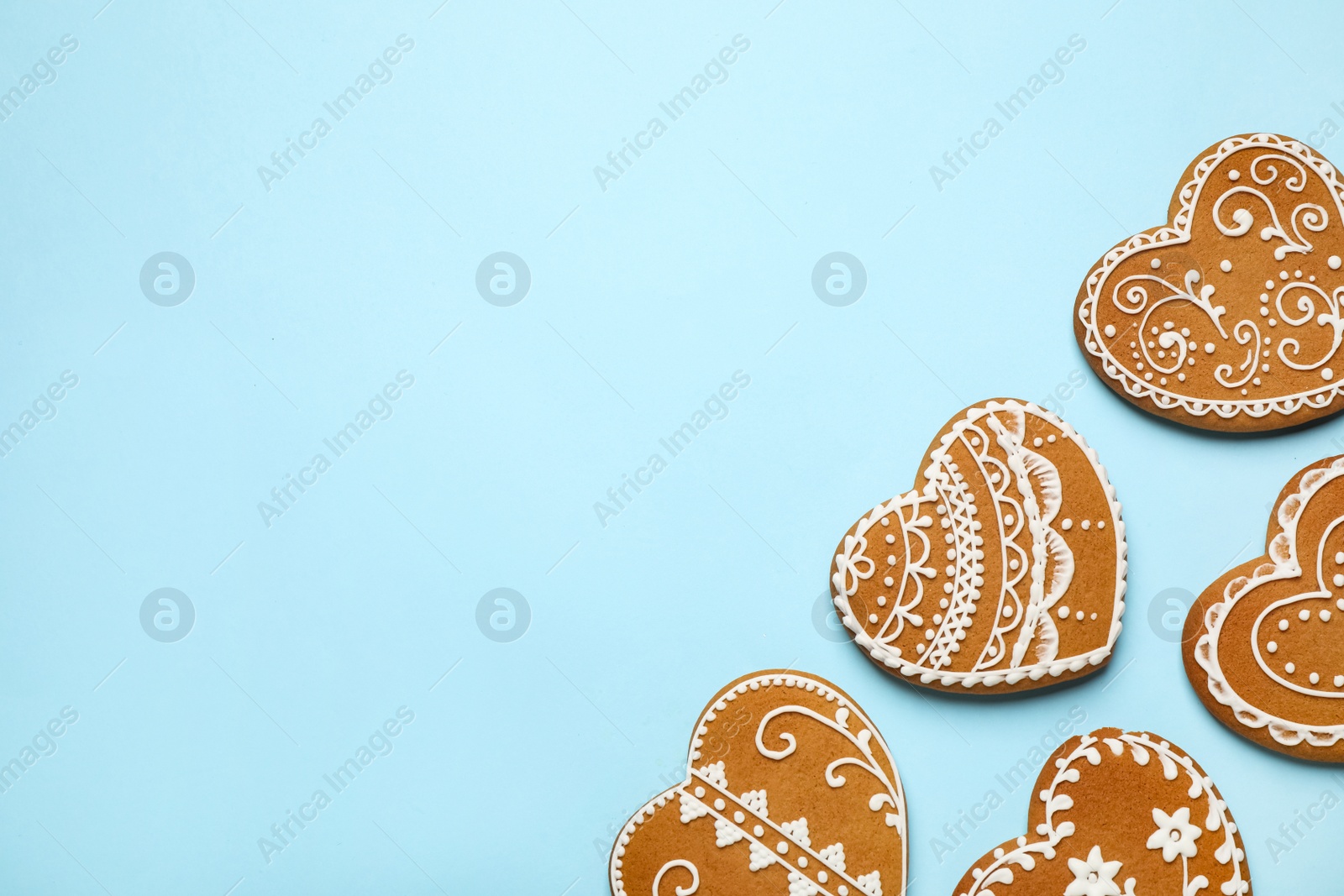 Photo of Tasty heart shaped gingerbread cookies on light blue background, flat lay. Space for text