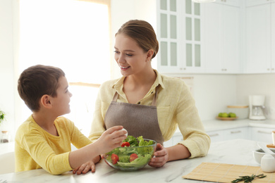 Mother and son cooking salad together in kitchen