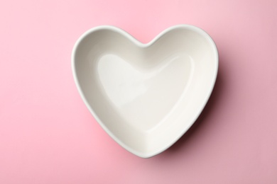 Photo of Heart shaped plate on color background, top view