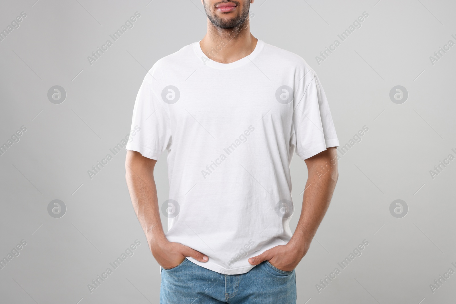 Photo of Man wearing white t-shirt on gray background, closeup