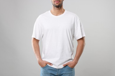 Man wearing white t-shirt on gray background, closeup