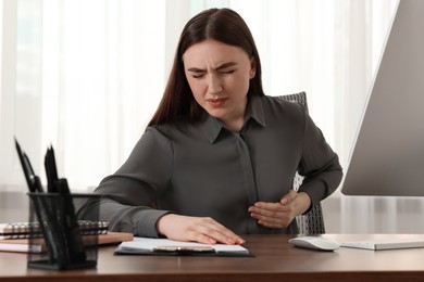 Woman having heart attack at table in office