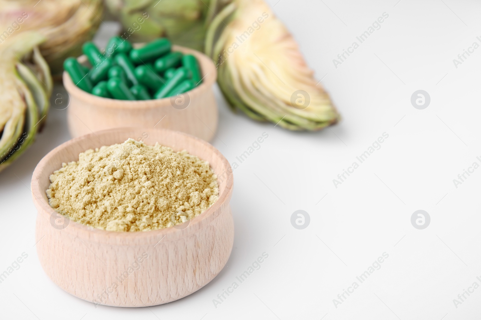 Photo of Bowls with pills, powder and fresh artichokes on white background, closeup. Space for text