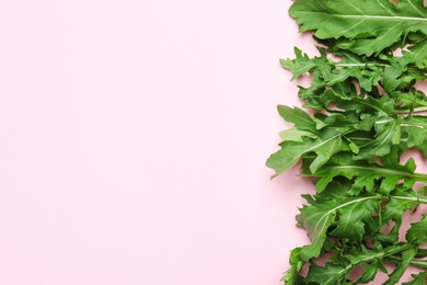 Fresh arugula on light pink background, flat lay. Space for text