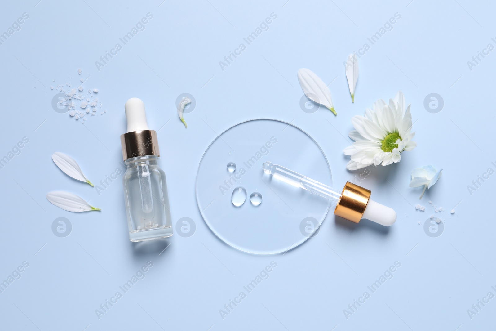 Photo of Bottle of cosmetic serum, pipette and flowers on light blue background, flat lay