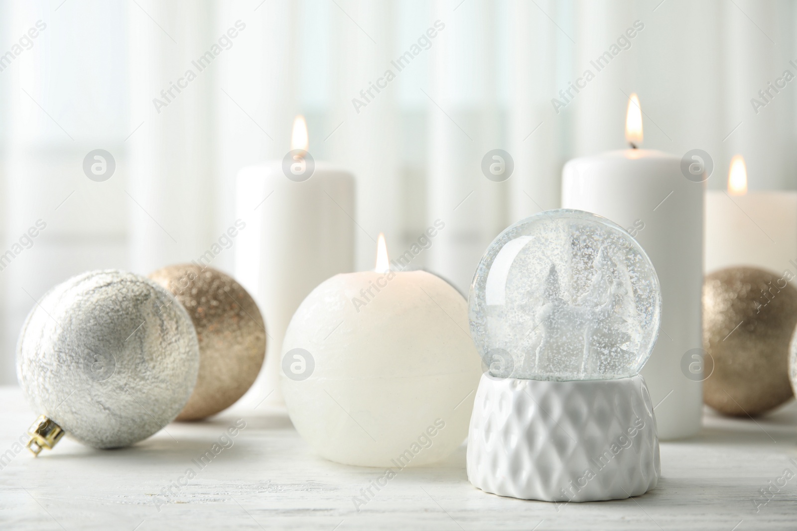 Photo of Snow globe with Christmas balls and candles on table. Space for text