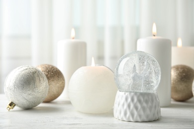 Photo of Snow globe with Christmas balls and candles on table. Space for text