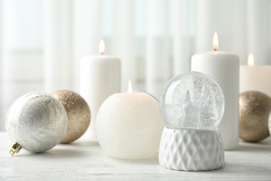 Snow globe with Christmas balls and candles on table. Space for text