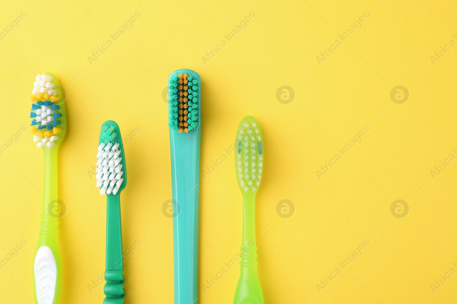 Photo of Many different toothbrushes on yellow background, flat lay. Space for text