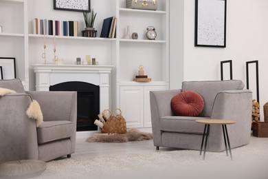 Photo of Comfortable armchairs, fireplace and shelves in living room. Interior design