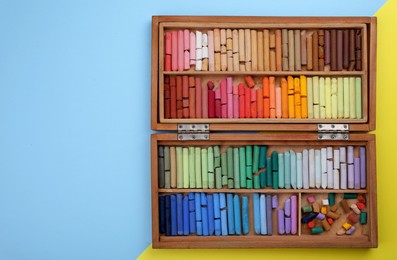 Photo of Set of soft pastels in wooden box on color background, top view with space for text. Drawing material