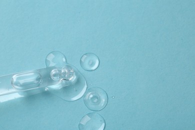 Photo of Pipette with samples of cosmetic serum on light blue background, above view. Space for text