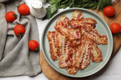 Photo of Delicious fried bacon slices and other products on white wooden table, flat lay
