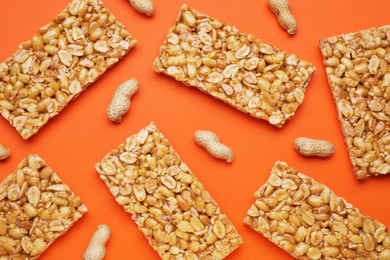 Photo of Tasty kozinaki bars and peanuts on orange background, flat lay