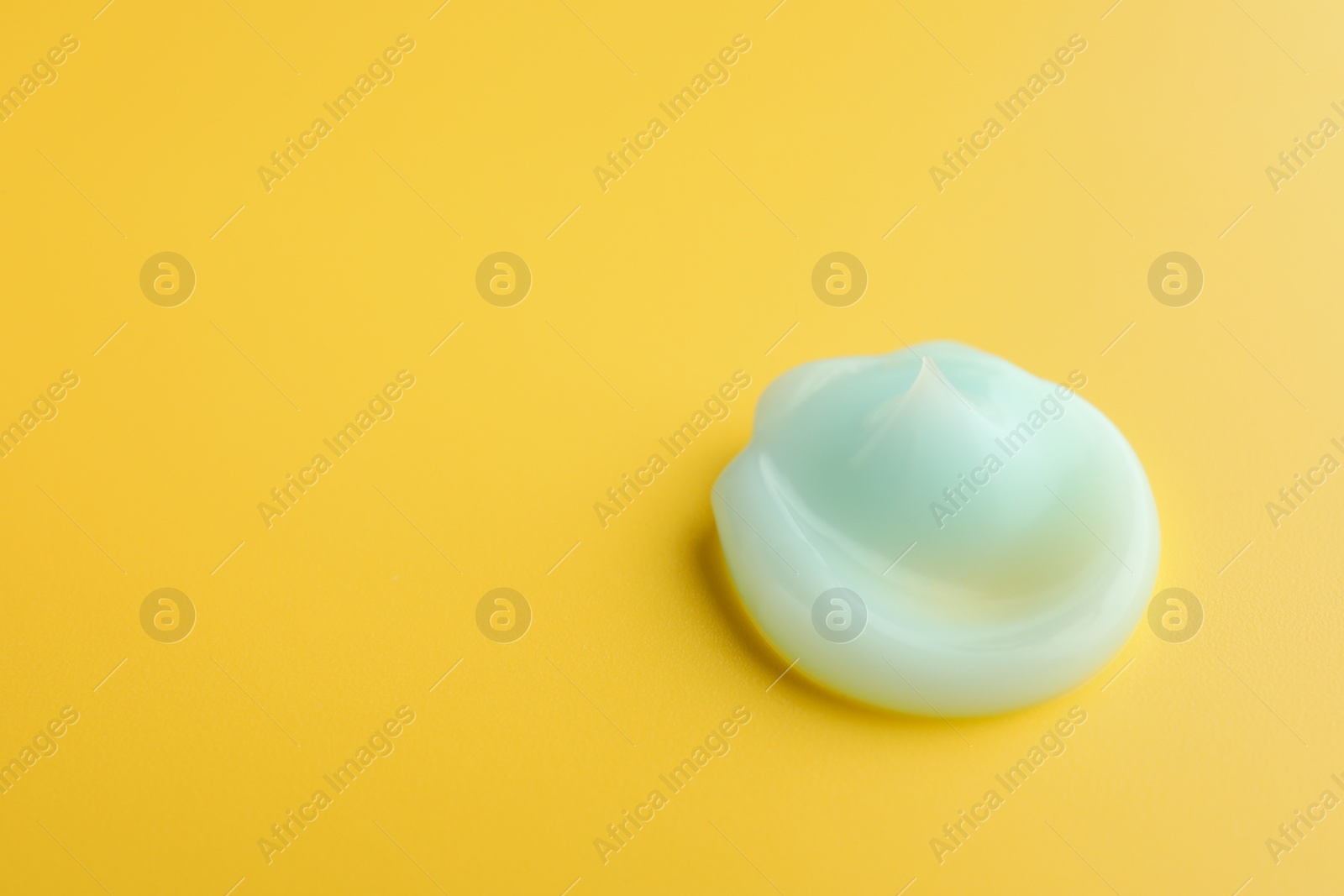 Photo of Sample of face cream on yellow background, top view. Space for text