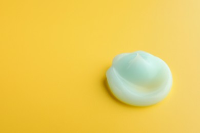 Sample of face cream on yellow background, top view. Space for text