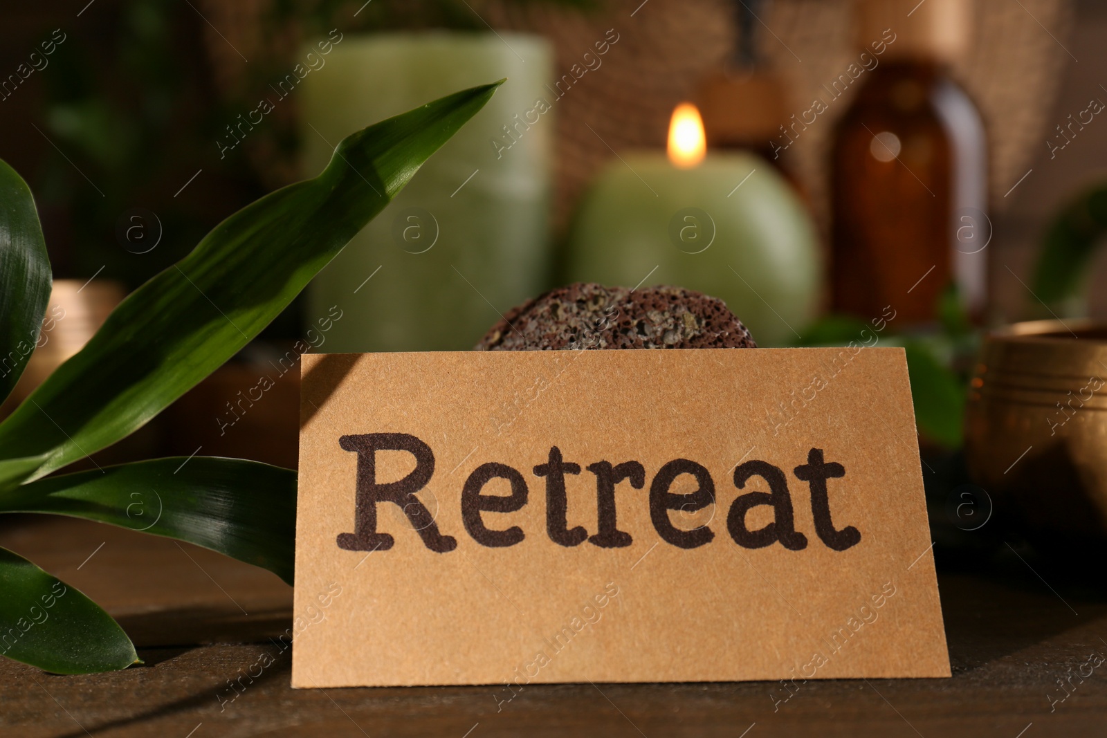 Photo of Card with word Retreat and green leaf on blurred background, closeup