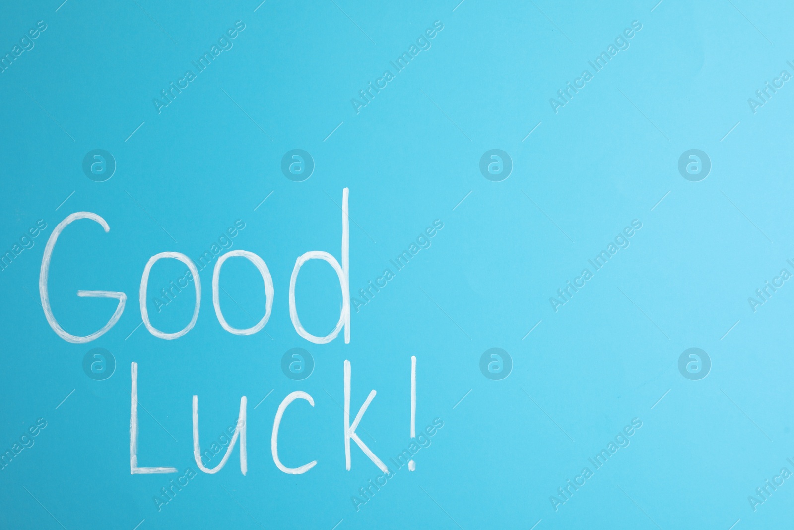 Photo of Phrase GOOD LUCK on light blue background, top view. Space for text