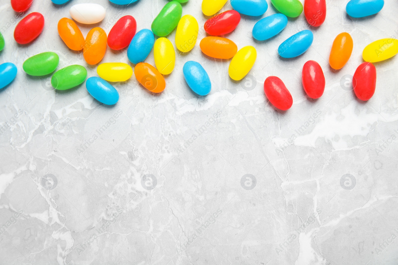 Photo of Flat lay composition with jelly beans on light background. Space for text