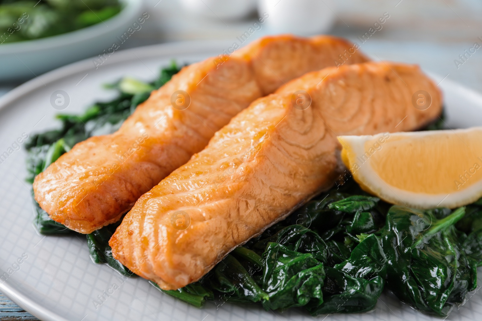 Photo of Tasty salmon with spinach and lemon on plate, closeup