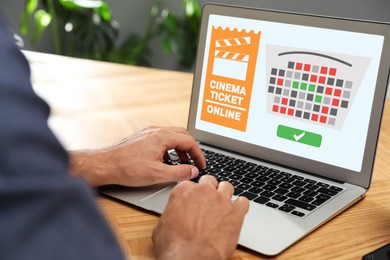 Man buying cinema tickets online via laptop at table, closeup