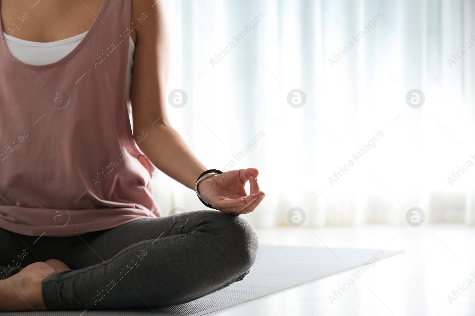 Photo of Woman practicing yoga on floor indoors, closeup. Space for text