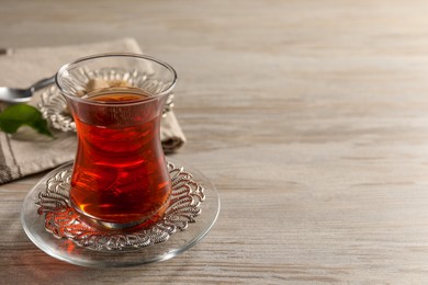 Glass of traditional Turkish tea on white wooden table, closeup. Space for text