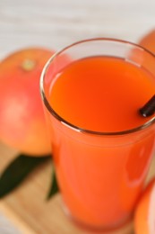 Photo of Tasty grapefruit juice in glass and fresh fruits on table, closeup