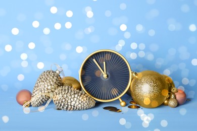 Stylish clock with Christmas decor on light blue background. New Year countdown