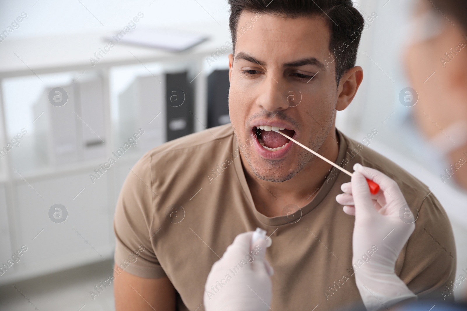 Photo of Doctor taking sample for DNA test from man in clinic