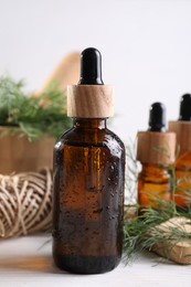 Bottles of essential oil and fresh dill on white wooden table, closeup