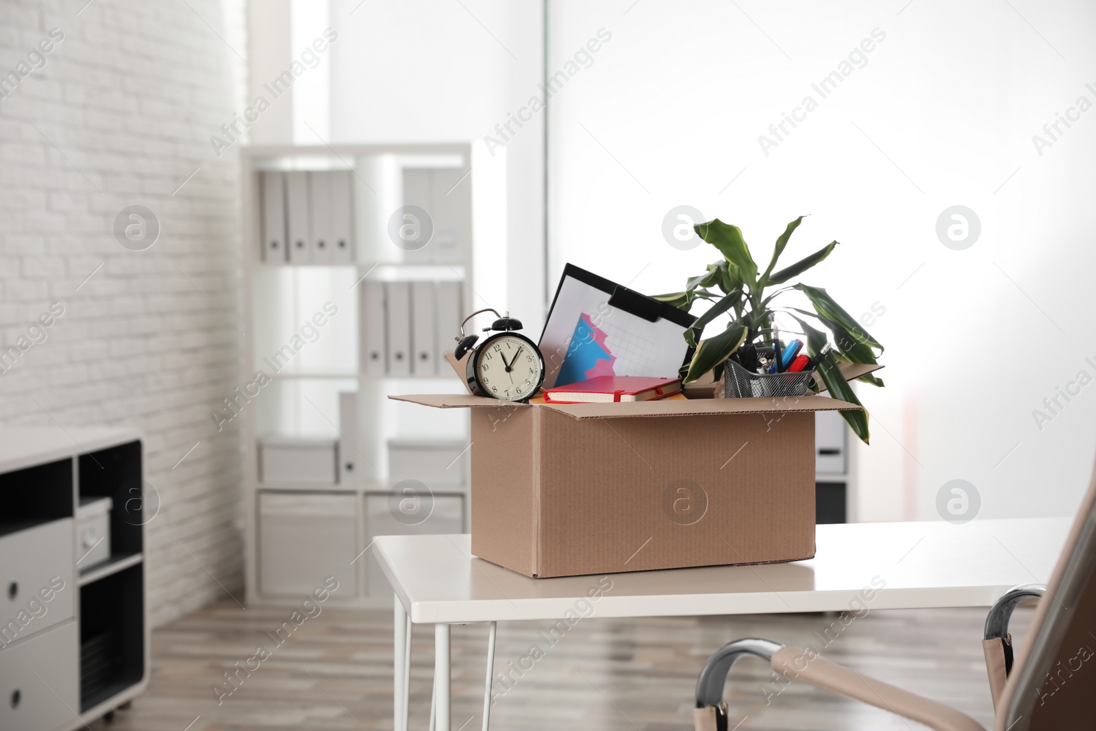 Photo of Cardboard box full of stuff on table in office