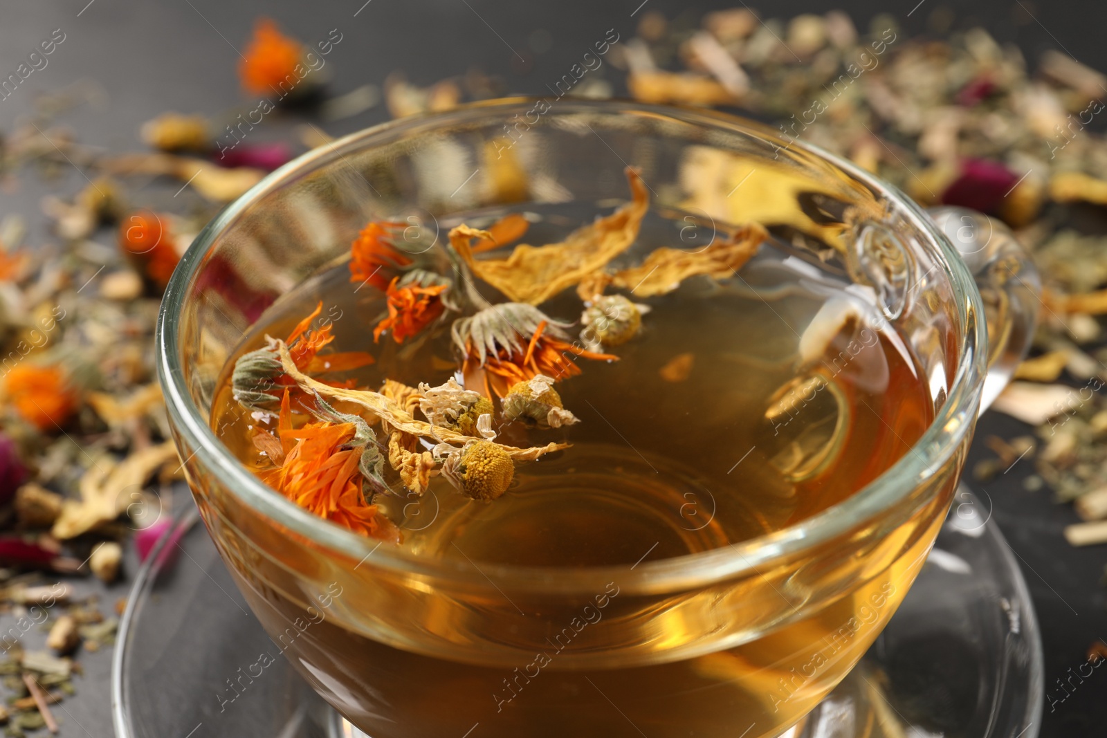 Photo of Freshly brewed tea and dried herbs on table, closeup