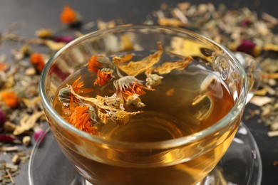 Photo of Freshly brewed tea and dried herbs on table, closeup