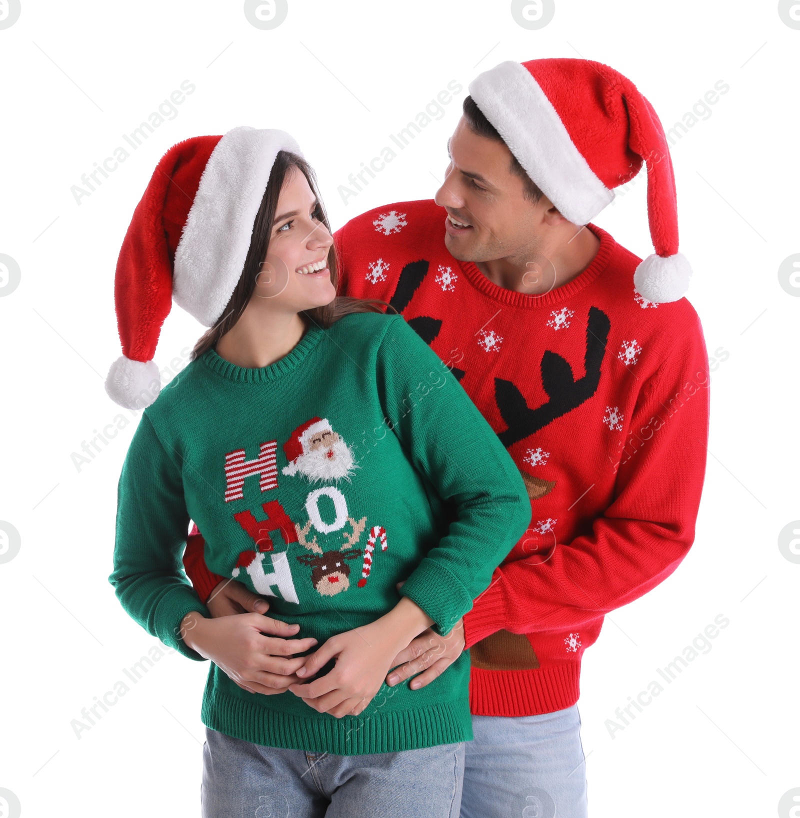 Photo of Beautiful happy couple in Santa hats and Christmas sweaters on white background