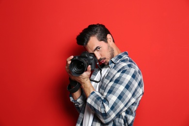 Photo of Emotional photographer with professional camera on red background