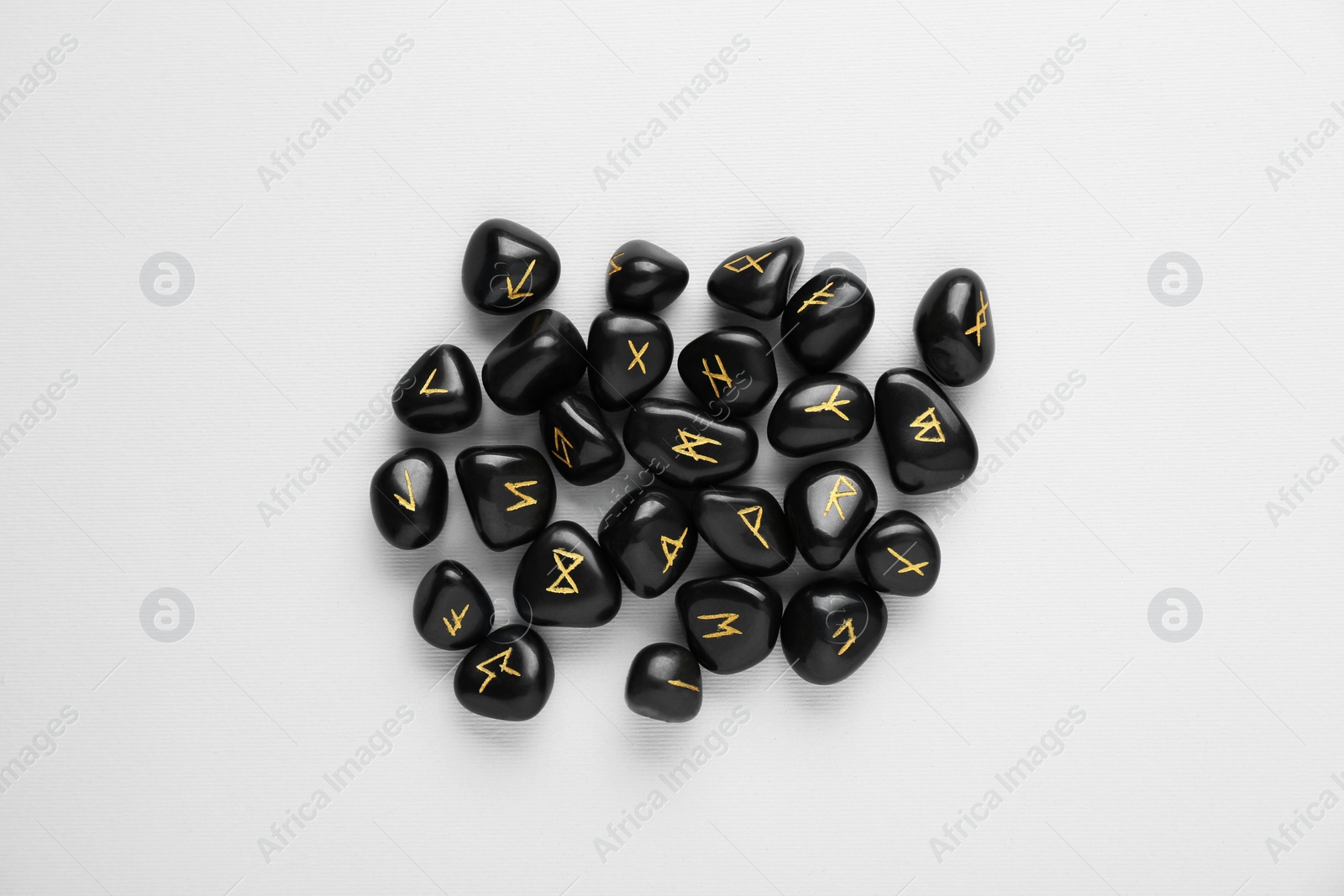Photo of Black rune stones on white background, top view