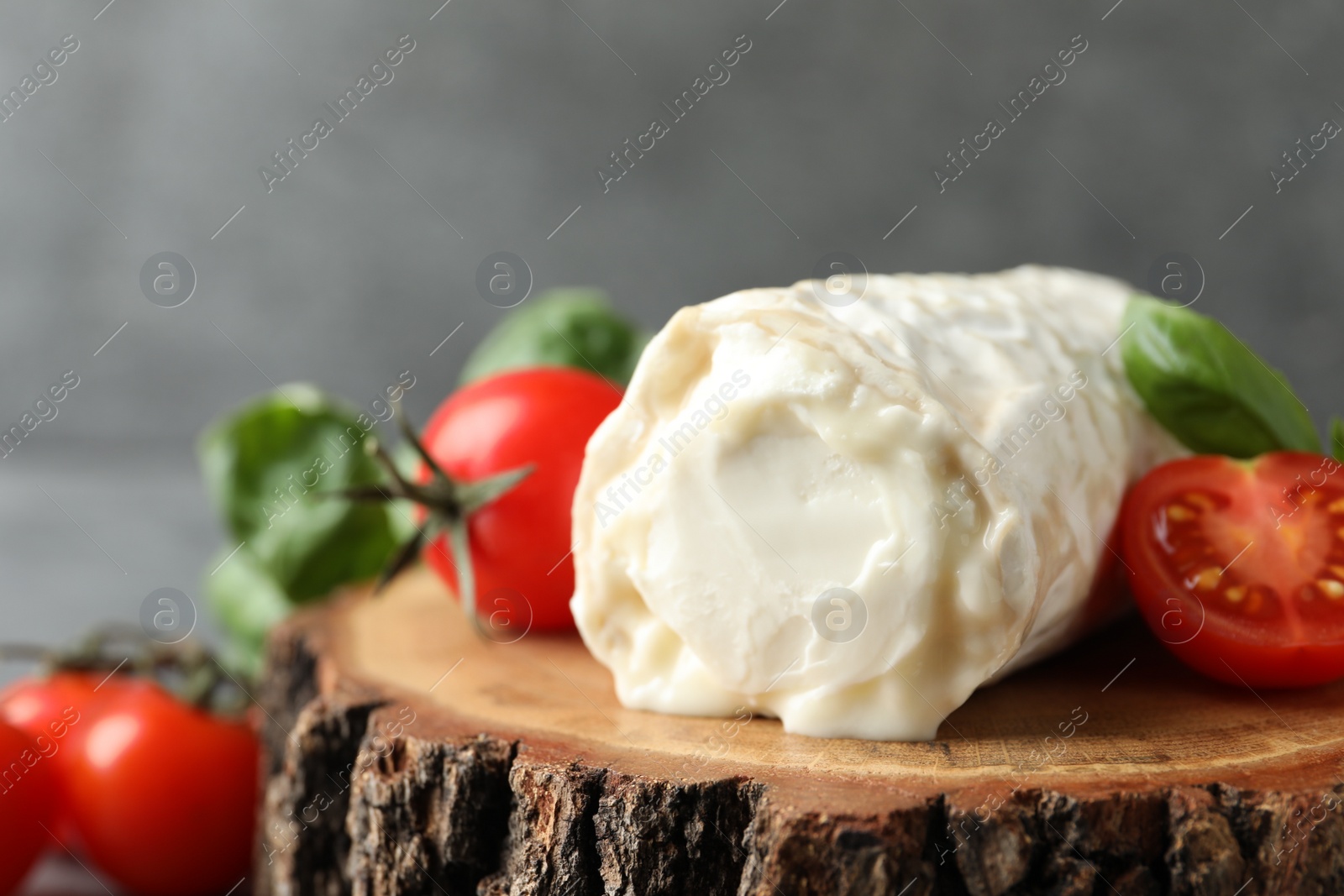 Photo of Delicious fresh goat cheese with tomatoes on wood, closeup