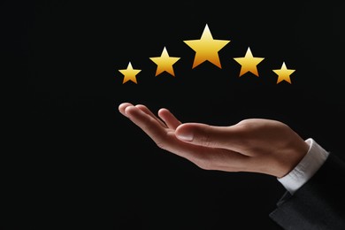 Man holding virtual stars on black background, closeup. Customer satisfaction score