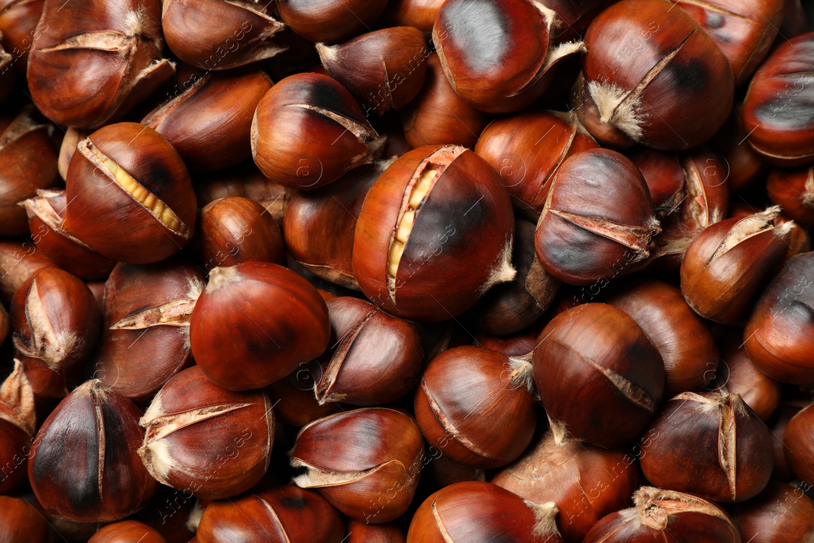 Photo of Pile of delicious edible roasted chestnuts as background, closeup