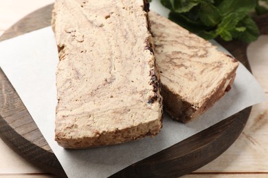 Photo of Pieces of tasty chocolate halva on wooden table, closeup