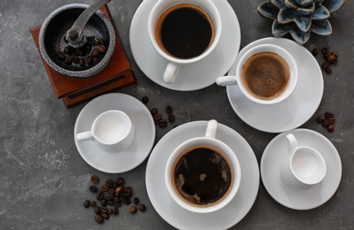 Photo of Cups of fresh aromatic coffee on grey background, top view